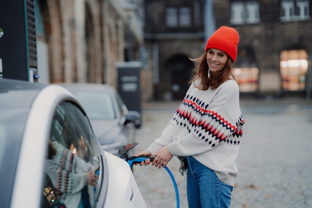 Chica cargando coche eléctrico